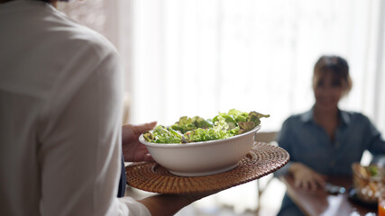 Adult SME owner work at busy small cafe bar pub on cozy day carry plate tray for group asia people friend party at vegan shop. Enjoy talk order fresh menu eat meal drink fine dish diet salad bowl.