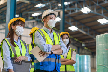 Group of Asian male and female engineers team wearing hygienic mask protect with helmet safety...