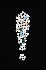 Exclamation mark made of pills on a black background. The concept of vaccination and health protection