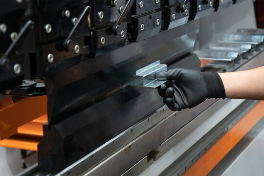 The hand of technician operator working with hydraulic press brake bending machine.