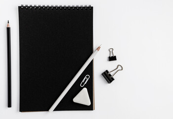 Black notebook blank mockup, pencils and stationery on white background. Top view, flat lay