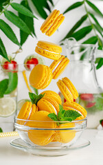 Yellow macaroons falling into the glass bowl. French dessert concept