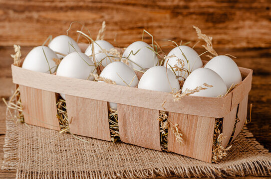 Fresh organic eggs in container on wooden background. Copy space