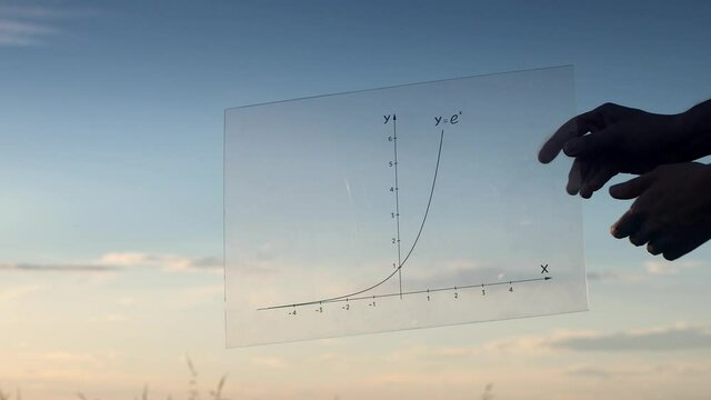 Young mathematician showing an exponential function graph against a sunset. Date of shooting day 29 June 2021 year. This video is a small part of a video about logarithms on channel "Pavel Kubarkov".