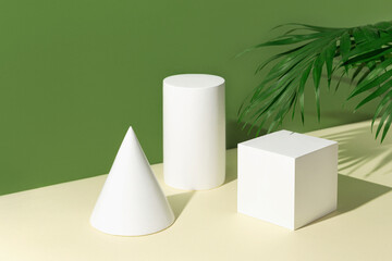 Abstract composition made of white geometric figures with palm tree leaf and shadows on pastel sunlit background. Minimal style