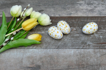 Osterhintergrund: Gelbe Tulpen und Ostereier auf einem Holzhintergrund.