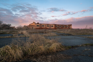 dry grass grows through the asphalt of an abandoned airfield in the Krasnodar territory and beautiful pink clouds at sunset