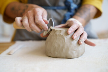 Creative handcraft process: female artist use tool for shaping and handmade sculpting of clay...