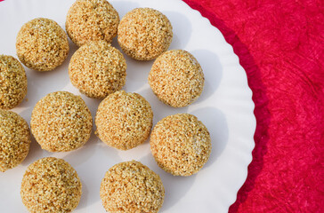 Delicious Rajgira laddu or Amaranth ladoo in white plate on pink background space to write text fonts. Makar sankranti food Indian sweet for traditional fasting. Pongal Lohri special food item