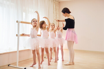 Coach teaches children. Little ballerinas preparing for performance by practicing dance moves