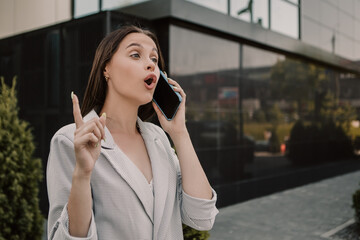 Small business owner office worker smiling happy woman standing outside building speak on phone with client. Female successful executive girl wait colleague meeting. Copy space.