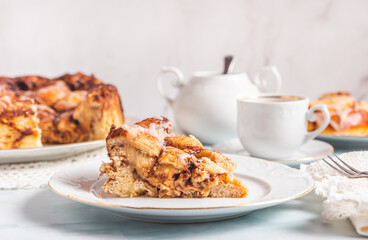 Portion of homemade cinnamon rolls on a white plate on a white table with coffee and pastry buns for breakfast. Traditional Swedish and Danish recipe.