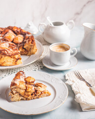 Portion of homemade cinnamon rolls on a white plate on a white table with coffee and pastry buns for breakfast. Traditional Swedish and Danish recipe.