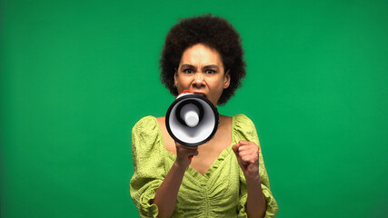 angry african american woman screaming in megaphone and looking at camera isolated on green
