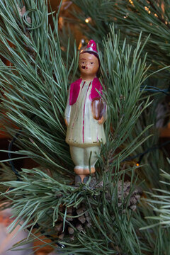 Christmas toy doll - Tajik girl authentic old Soviet 1070s glass Christmas tree toy on a clothespin on a spruce branch close-up.