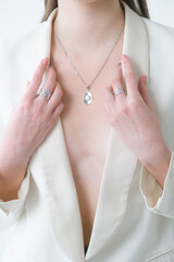 Trending silver jewelry set on a beautiful young girl in a white fashionable jacket  with long dark hair. Beauty and fashion 
