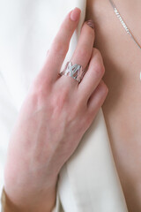 Trendy silver ring on a beautiful young girl in a white fashionable jacket. Beauty and fashion 
