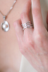 Trendy silver ring on a beautiful young girl in a white fashionable jacket. Beauty and fashion 
