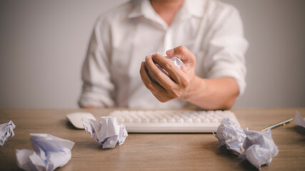 A frustrated discouraged man crumpling a paper at work on the desk.