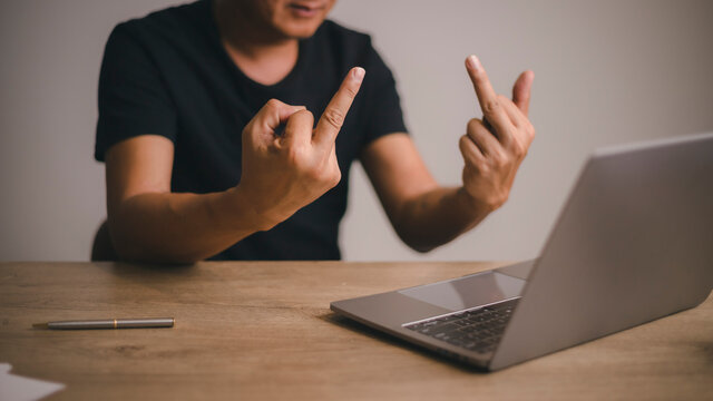 Fuck you. angry young big boss, working and making video call on a laptop, showing fucker and have conflict to the companion.