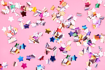 Bright colorful star-shaped confetti sparkles on a pink background.