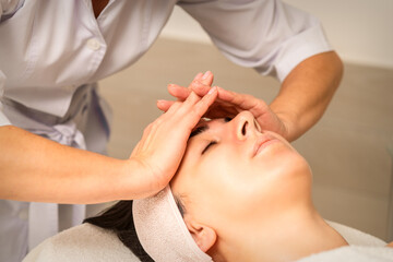 Fototapeta na wymiar Beautiful young caucasian woman receiving a head massage in a beauty clinic, close up