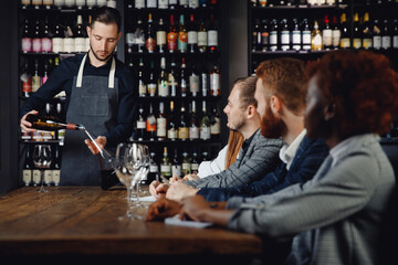 Male sommelier conducts red wine tasting for restaurant guests