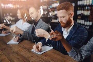 Closeup tasting red wine sommeliers and taking notes at degustation notepad