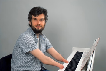 Life of handicapped person musician with disabilities. Disabled brunet man with amputated two stump hands is playing piano by notes looking at camera and smiling. Trying to keep playing after injury.