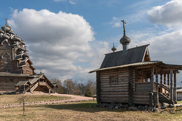 Old wooden chapel and church in the suburbs of the Russian city of St. Petersburg against the background of a blue cloudy sky