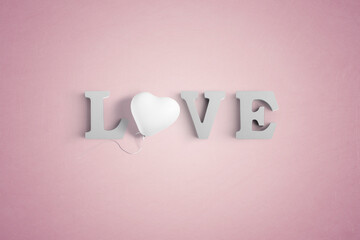 Wooden letters spelling LOVE with a heart shaped white balloon