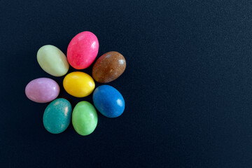 Sweets and confetti arranged in the shape of a flower. Confetti of different color and taste. Dark blue and black background with copy space available.