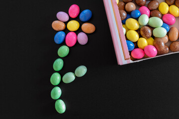 Sweets and confetti arranged in the shape of a flower. Confetti of different color and taste. Dark...