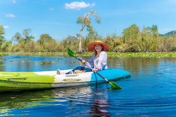 Asian woman kayaking on the river to see nature during the holidays.