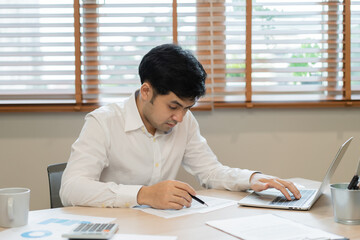 Smart, smile asian young businessman, male, working and pressing calculator to calculate tax income and expenses, bills, credit card for payment or payday at home, office. Financial, finance concept.