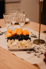 Festive table with candlestick, white tablecloth, black olives and cheese.