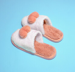 Home soft female slippers close-up pink with white on a blue background.