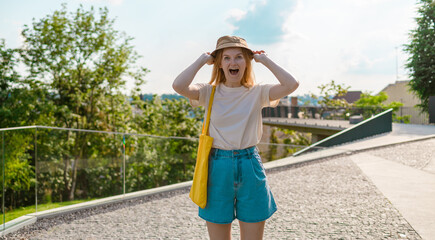Fototapeta premium Beautiful happy young blonde female in stylish clothes smiling at the camera on a sunny summer day