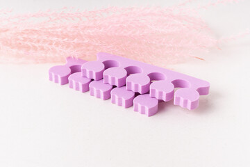 Purple toe dividers and pink dried flowers. Tool for pedicure. Soft styrofoam