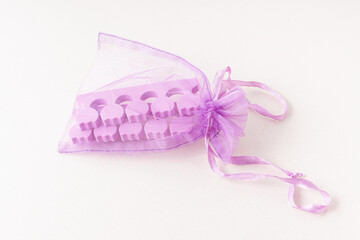 Purple toe dividers in mesh pouch. Tool for pedicure. Soft styrofoam. Travel kit