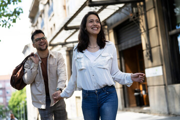 Husband and wife outdoors. Girlfriend and boyfriend walking in the city. Couple enjoy in sunny day.