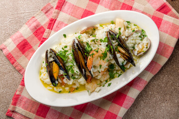 risotto with seafood on white plate on brown concrete table top view