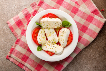 Caprese salad with mozzarella and tomato and basil top view on brown concrete table