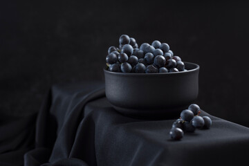 Uvas azules dentro de un recipiente negro sobre fondo negro