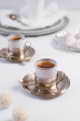 Dos tazas de té clásico con dulces chocolates blancos cubiertos de coco en el cuadro blanco