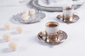 Fototapeta na wymiar Dos tazas de té clásico con dulces chocolates blancos cubiertos de coco en el cuadro blanco