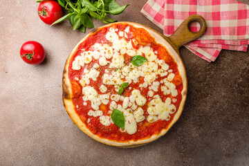 Italian pizza Margherita with tomato sauce and basil on brown concrete table