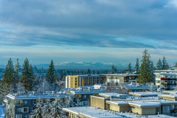 Crispy winter morning cityscape view from Univercity Highlands on Burnaby Mountain across high-rise city buildings to distant  alpine mountains on horizon.