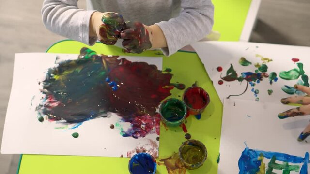 Children draw with finger paints in kindergarten or home, close up. Concept of child development.