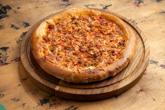 Meat pizza on a wooden table.